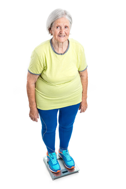 年配の女性の体重計で体重を計って - 写真・画像
