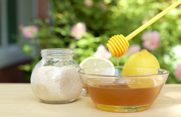 Schüssel mit Honig und Zucker und Zitronen auf Holztisch - Foto, Bild