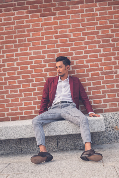 Handsome Asian model sitting in the city streets - Foto, afbeelding