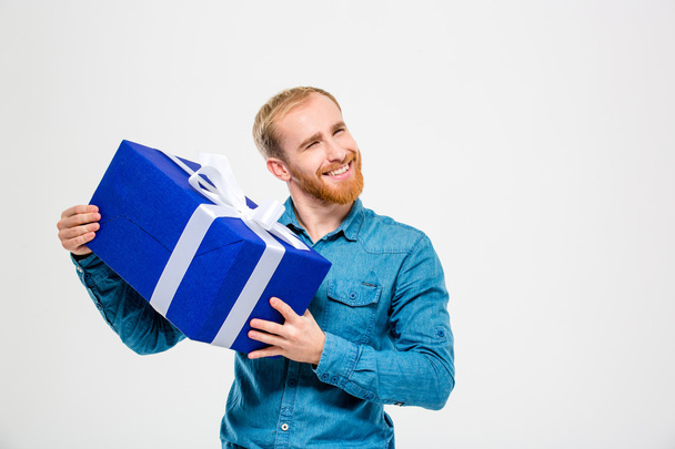 Happy cheerful man with beard holding a present - Foto, afbeelding