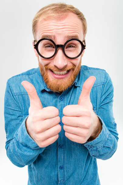 Funny cheerful bearded man in round glasses showing thumbs up - 写真・画像