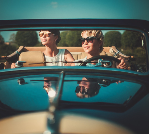Kaksi tyylikästä naista klassisessa avoautossa
  - Valokuva, kuva