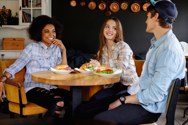 Vrolijke multiraciale vrienden eten in een café  - Foto, afbeelding