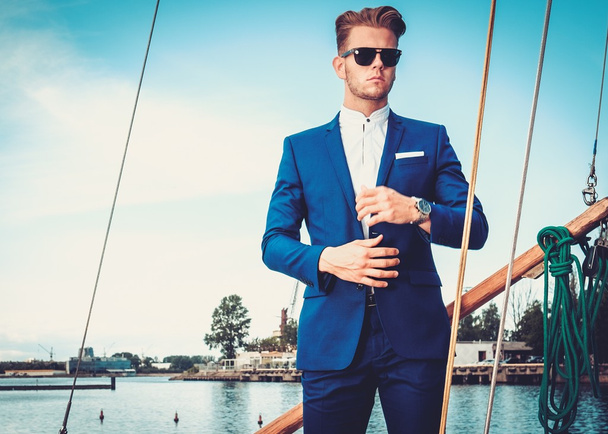 Stijlvolle rijke man op een luxe houten regatta   - Foto, afbeelding