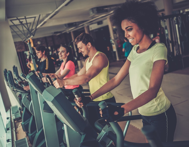 Pessoas se exercitando em uma cardio máquinas de treinamento em um ginásio
 - Foto, Imagem