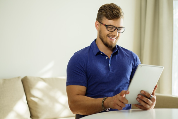 Hombre guapo usando tableta PC en casa
  - Foto, Imagen