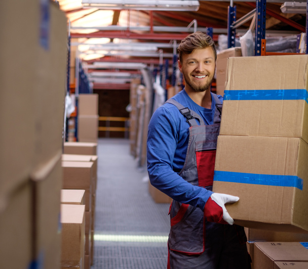 Porter carrying boxes in a warehouse  - Valokuva, kuva