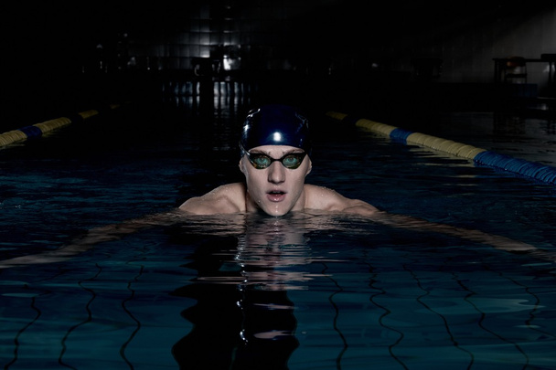Sportman zwemt in een zwembad - Foto, afbeelding