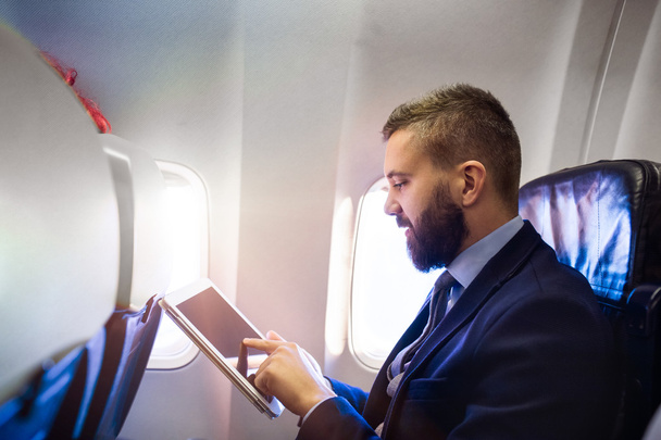 Empresário em avião com tablet
 - Foto, Imagem