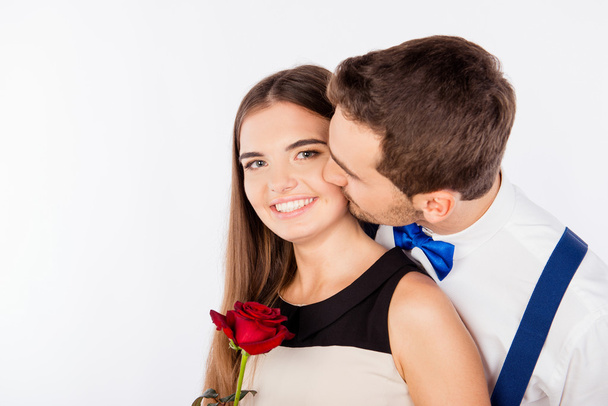 Roztomilý mladý muž líbá svou přítelkyni s růží  - Fotografie, Obrázek
