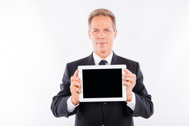 Confident aged man in business suit showing a screen of tablet - Fotó, kép