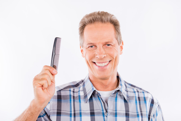 Confident aged man holding a comb - Foto, afbeelding