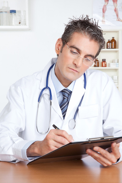 Male Doctor Writing on Clipboard - Фото, изображение
