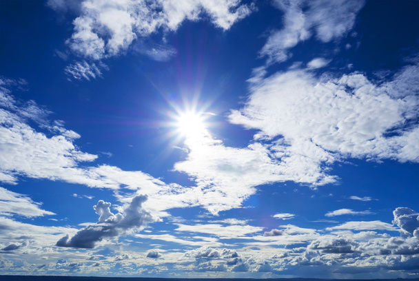 sun flare surrounded by the beautiful cloudy blue sky - Photo, Image
