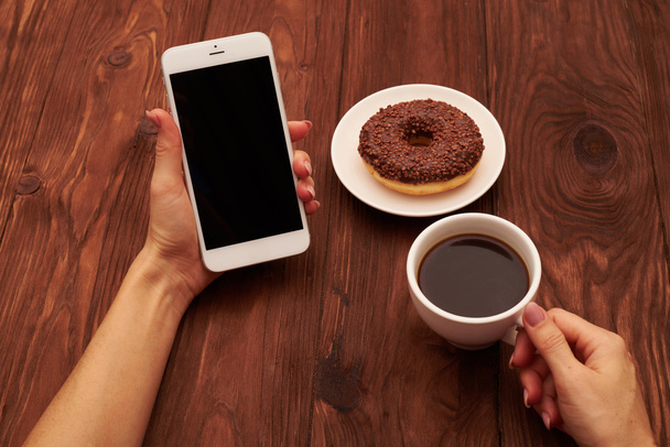 kadının el smartphone ve kahve fincan tutarak yakın çekim fotoğraf - Fotoğraf, Görsel