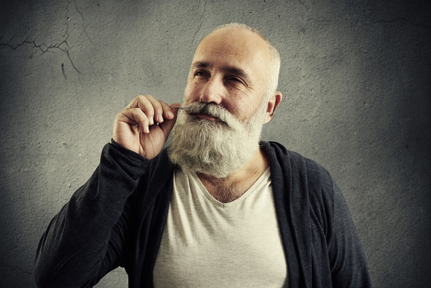 sonriente hombre mayor torciendo su bigote
 - Foto, Imagen