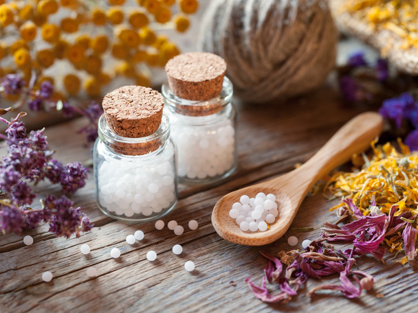 Bottles of homeopathy globules, spoon and dry healthy herbs - Photo, image