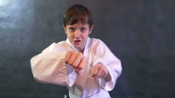 nastoletni chłopiec w ręce walki karate kimono macha pięściami slow motion - Materiał filmowy, wideo