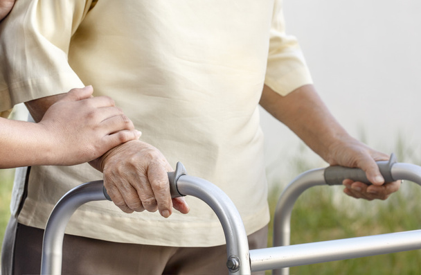 mujer mayor usando un andador con cuidador
 - Foto, Imagen