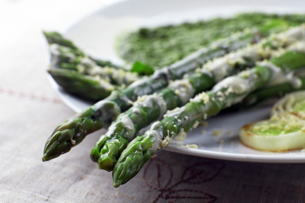 Delicious asparagus dish with onions and green sauce on the table, close up - Zdjęcie, obraz