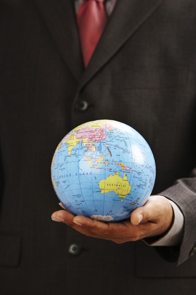 Man holding a desk globe on the palm - Foto, afbeelding