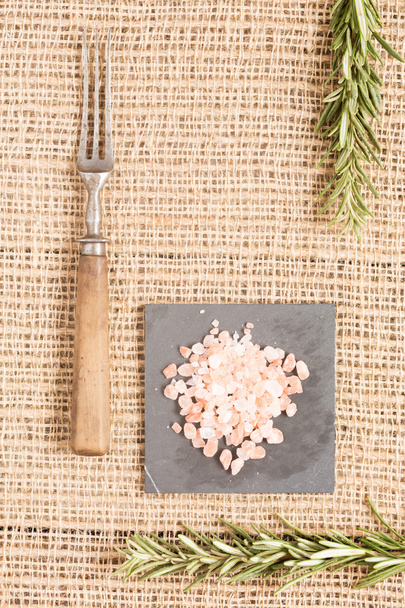 Pink himalaya salt on dark plate with rosemary and antique fork - Photo, Image