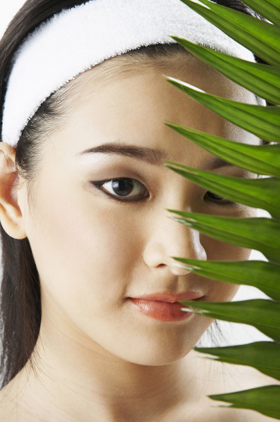 Young woman wearing towel, holding green leaf - Foto, Imagem