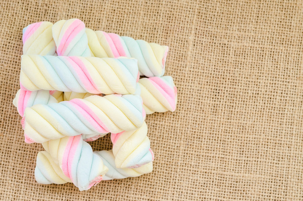 Twisted marshmallow on sack background. - 写真・画像
