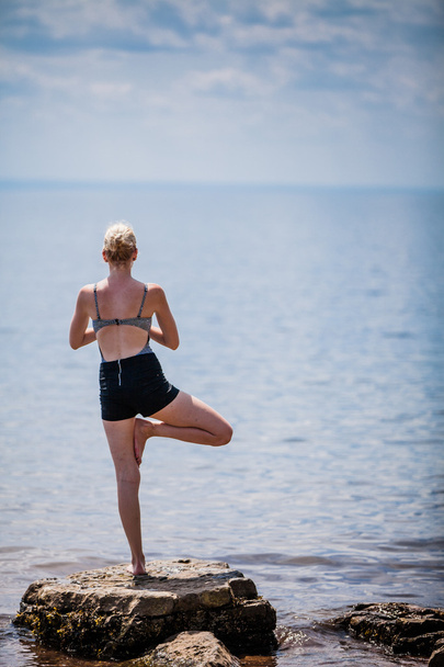 Vrouw doet Yoga boom positie - Foto, afbeelding