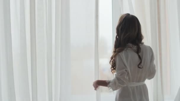 νεαρή γυναίκα να στέκεται στο παράθυρο - Πλάνα, βίντεο