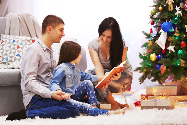 Happy family read book in the decorated Christmas room - Фото, изображение