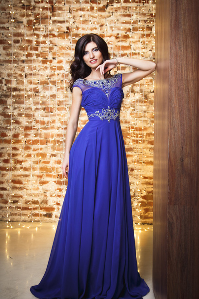 Portrait of gorgeous woman in luxury blue dress over christmas background - Fotó, kép