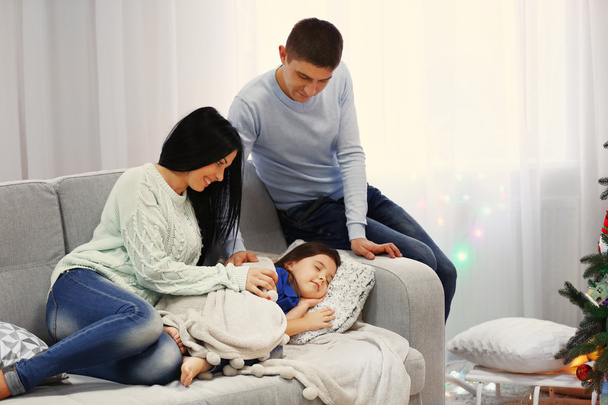 Parents and sleeping daughter in the decorated Christmas room - Foto, Imagen
