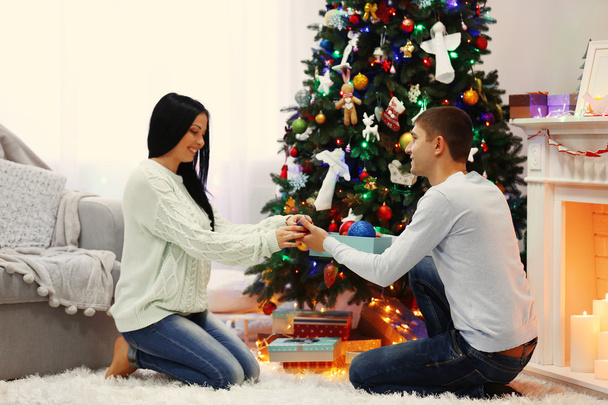 Happy couple on the floor with gifts in the decorated Christmas room - 写真・画像