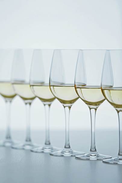 Wijnglazen met witte wijn op houten tafel op lichte achtergrond - Foto, afbeelding