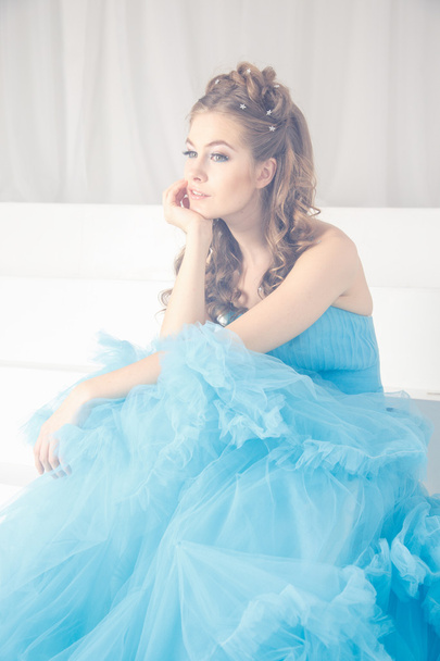 Beautiful young woman in gorgeous blue long dress like Cinderella with perfect make-up and hair style - Фото, изображение