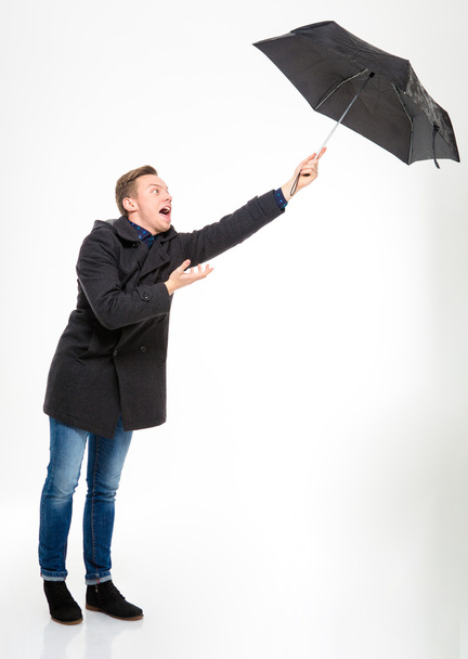 Anxious stressed young man with umbrella flying away - Fotó, kép
