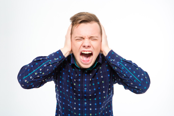Hysterical mad young man closed ears with hands and screaming  - Photo, Image