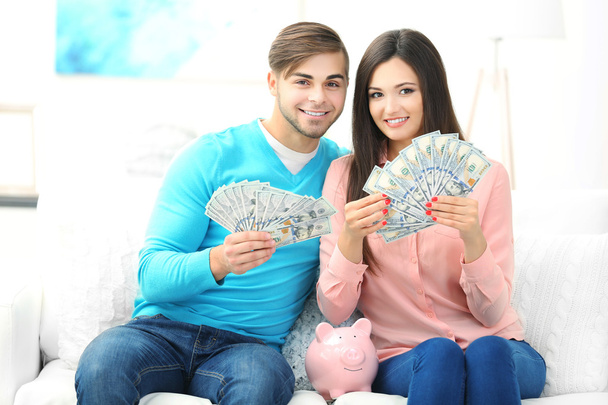 Happy couple sitting at home and counting money from the pig money box - Фото, зображення