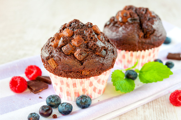 Pair of delicious chocolate muffins with chocolate and berries - Photo, Image