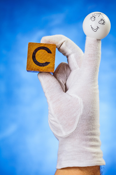Marionnette à doigts tenant un cube en bois avec lettre majuscule C
 - Photo, image