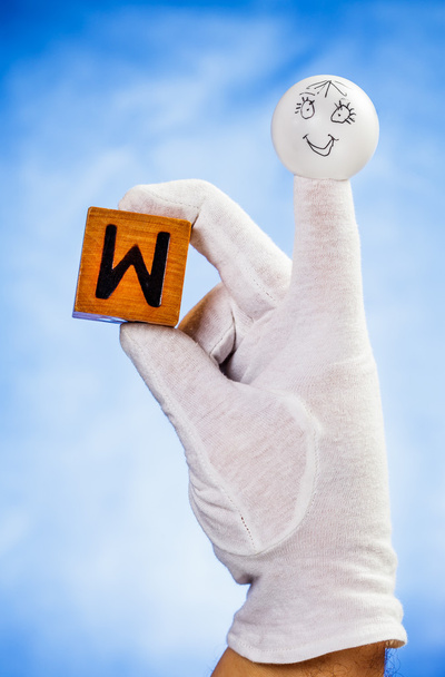 Marionnette à doigts tenant un cube en bois avec lettre majuscule W
 - Photo, image