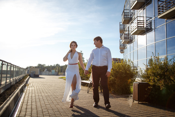Belo casal homem e mulher descansa e caminha juntos perto do edifício de luxo em um dia de verão
 - Foto, Imagem