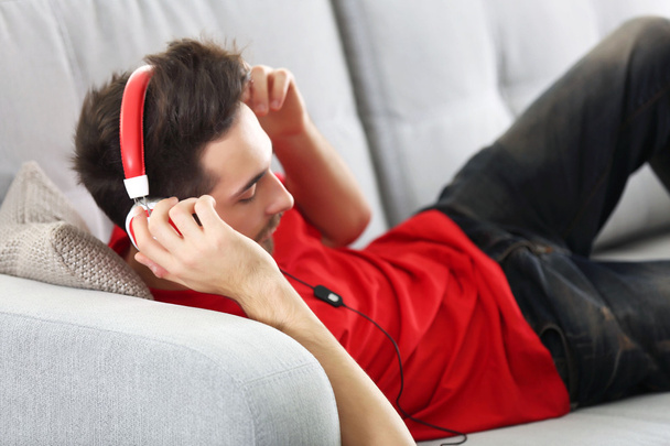 Young man listens music with headphones  - Фото, изображение