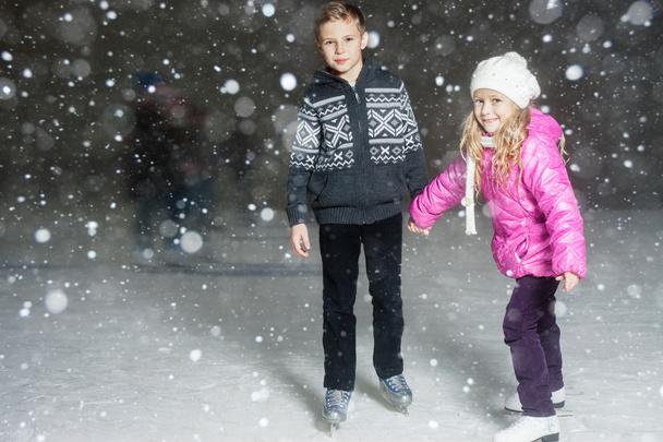 Happy children ice skating at ice rink, winter night - Fotó, kép