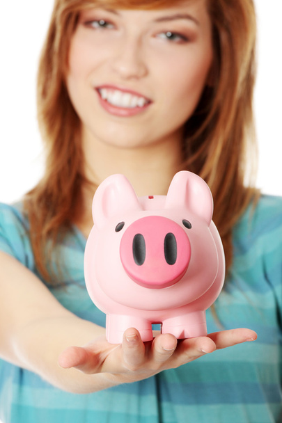 jonge tiener vrouw toont haar roze piggy bank - Foto, afbeelding