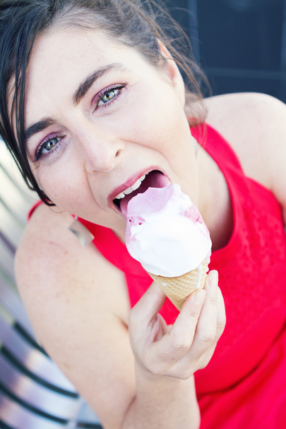 Gros plan d'une femme mangeant une glace dans une robe rouge
 - Photo, image