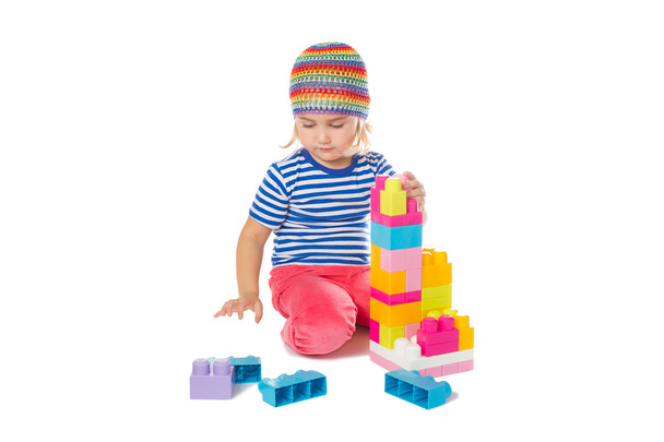 Little girl in a colorful shirt playing with construction toy b - Фото, изображение