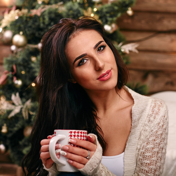 Portrait of happy young woman with cup near christmas tree - Fotografie, Obrázek