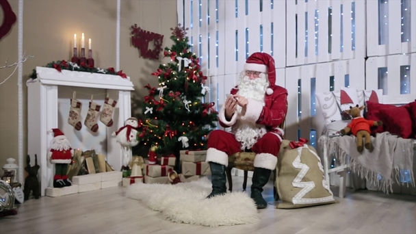 Santa εργασία στο τηλέφωνο, δωμάτιο με τζάκι και χριστουγεννιάτικο δέντρο, δώρα - Πλάνα, βίντεο